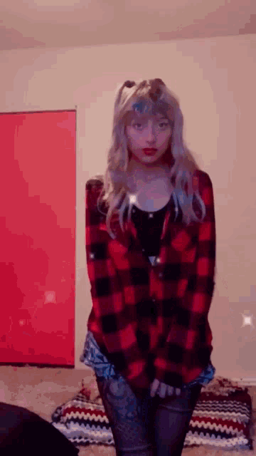a woman in a plaid shirt is standing in a room with her hands in her pockets .