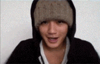 a man wearing a hooded jacket and a beanie is smiling