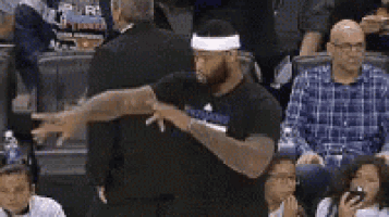 a referee is talking to a basketball player in the stands during a basketball game .