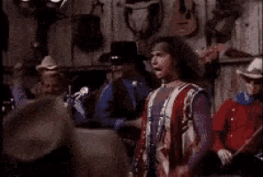 a man in a cowboy hat is dancing in a crowd of people .