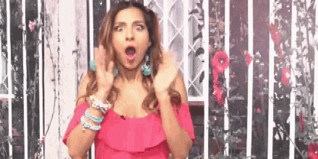 a woman in a pink dress is making a surprised face with her mouth open .