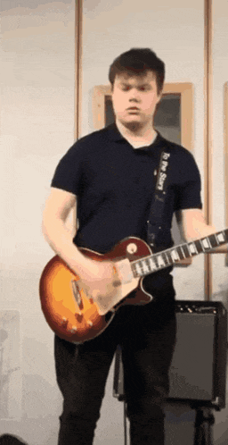 a man in a blue shirt is playing a guitar with a black strap that says black star on it