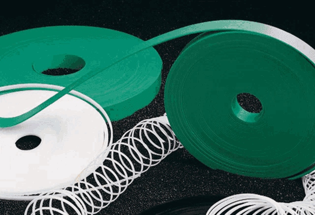 several rolls of green and white ribbon are laying on a black surface