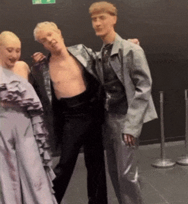 a man without a shirt is standing next to two women