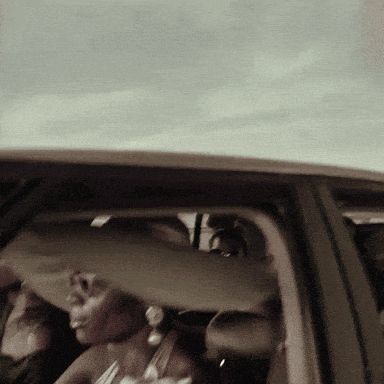 a woman sits in the back seat of a car with her head out the window