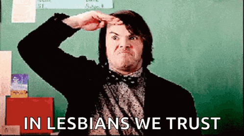 a man salutes in front of a green board with the words in lesbians we trust written on it