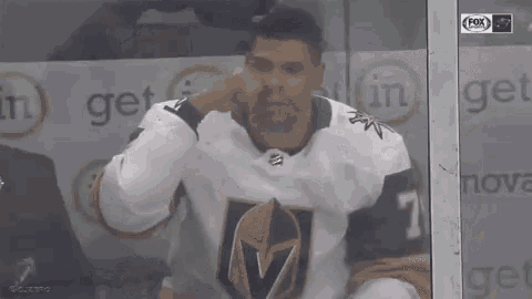 a hockey player is talking into a microphone while sitting in a locker room .
