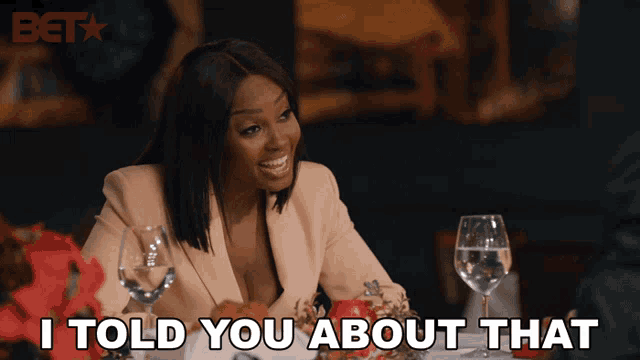 a woman is sitting at a table with wine glasses and says i told you about that