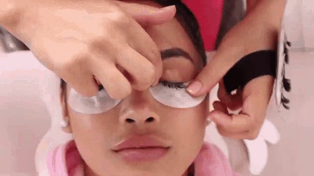 a woman is getting her eyelashes done by a woman in a beauty salon .