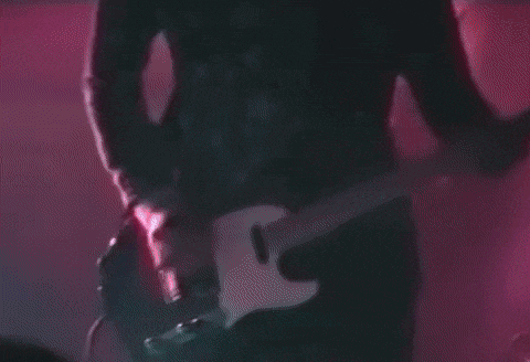a man in a green and white shirt is playing a guitar on stage .