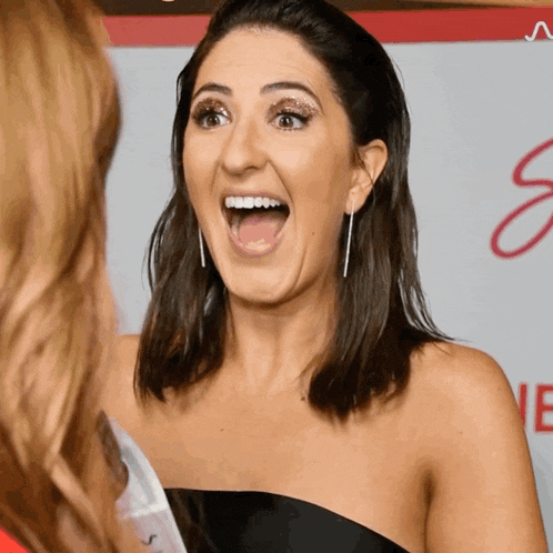 a woman with a surprised look on her face stands in front of a sign that says ' s ' on it