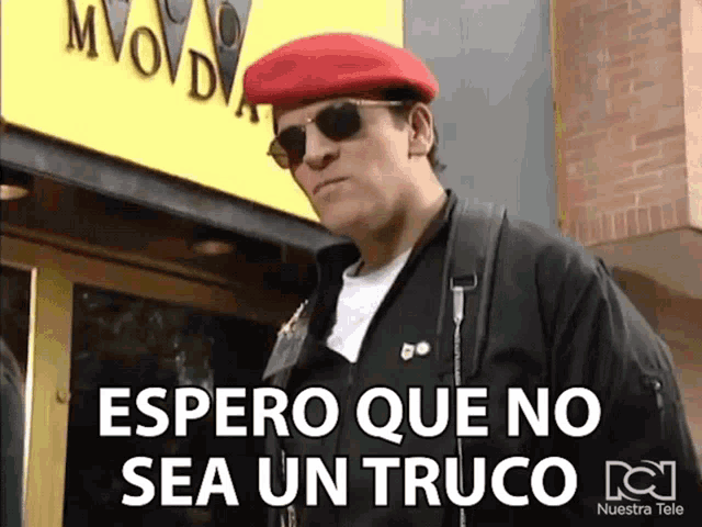 a man wearing a red beret and sunglasses is standing in front of a yellow sign that says movado