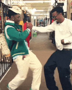 two men are dancing in a store with one wearing a hat that says ' ers ' on it
