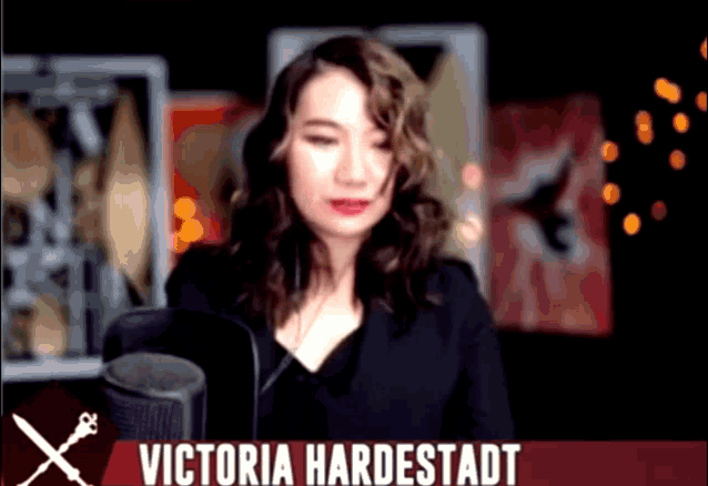a woman in front of a microphone with the name victoria hardestadt on the bottom right