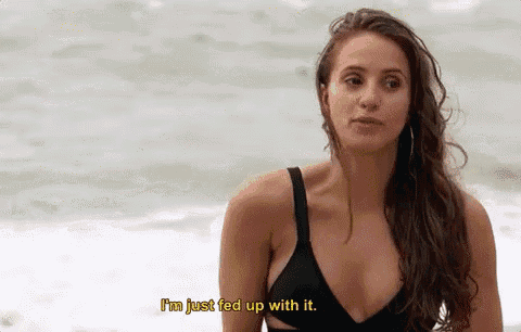 a woman in a black bikini is standing on the beach and says i 'm just fed up with it .