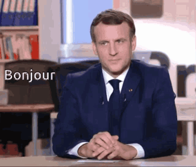 a man in a suit and tie is sitting at a desk with the word bonjour written on it