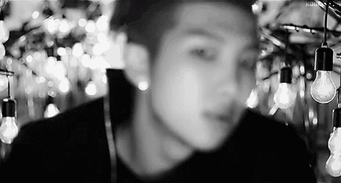 a black and white photo of a man in front of a bunch of light bulbs .