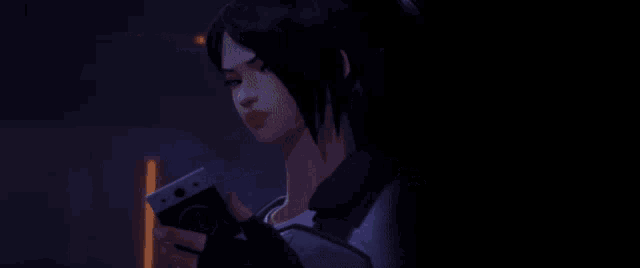 a woman is holding a cell phone in her hand and looking at it .