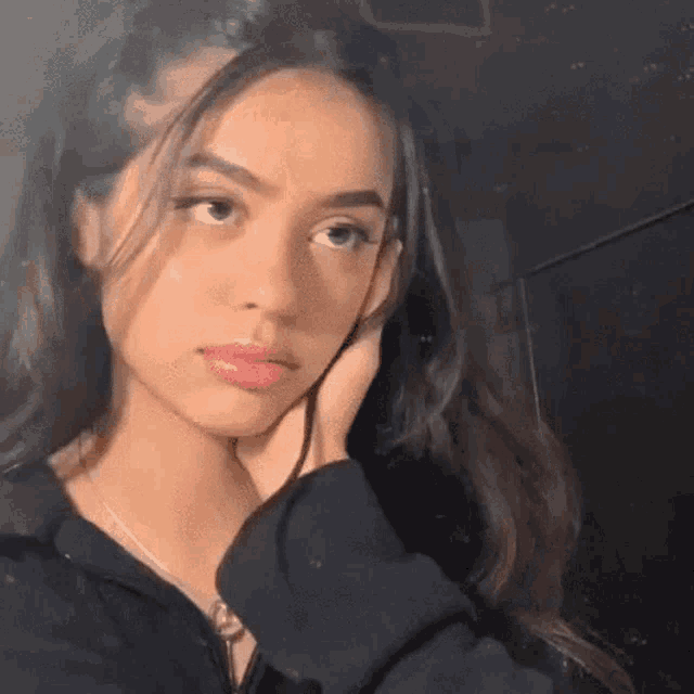 the girl is wearing a black hoodie and a necklace .