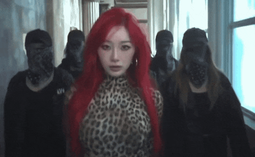 a woman with red hair is standing in a hallway with a group of people standing around her .