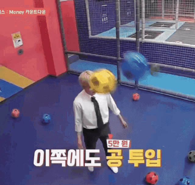 a man in a suit and tie is kicking a soccer ball on a trampoline ..