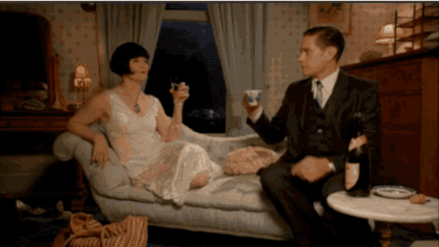a man and a woman are sitting on a couch toasting with champagne