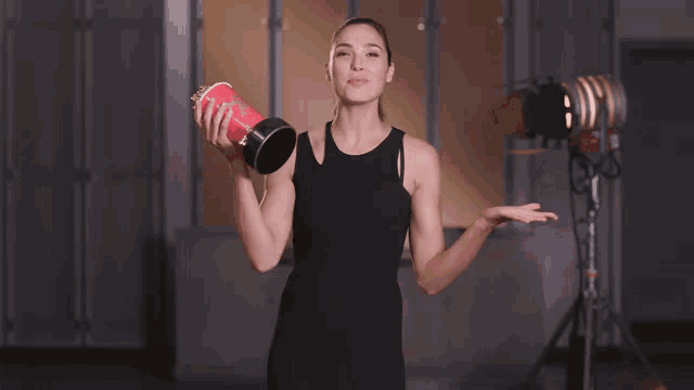 a woman in a black dress is holding a red cup with popcorn on it