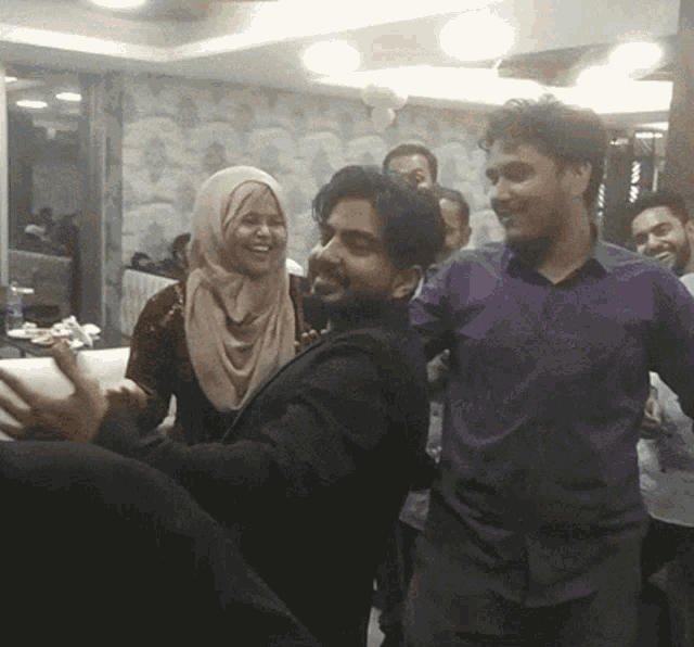 a group of people are dancing together in a room with a woman wearing a hijab
