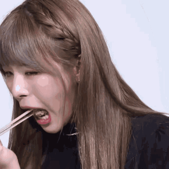 a woman with a braided headband is eating food with chopsticks