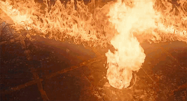 a large fire is coming out of a hole in the ground .