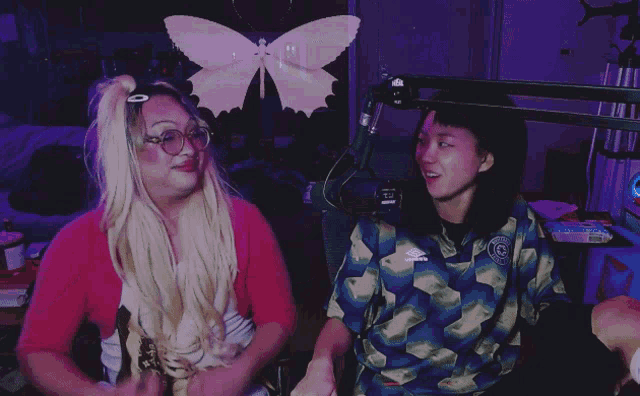 a woman wearing a blue umbro shirt stands next to another woman wearing a pink butterfly headband