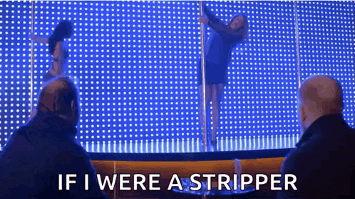 a woman is dancing on a pole in front of a crowd of people while a man watches .