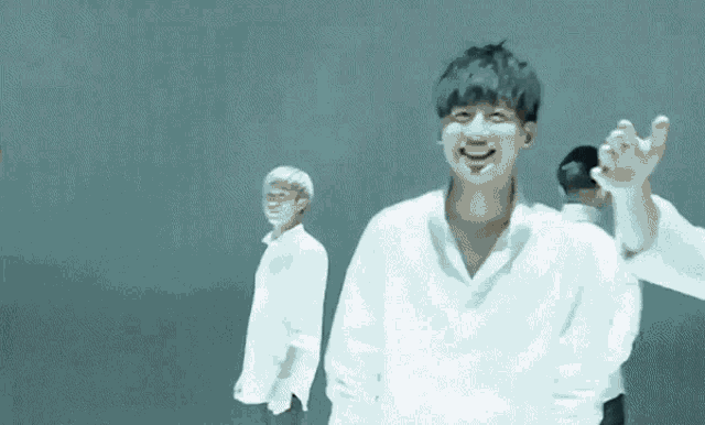 a man in a white shirt is making a funny face while standing next to two other men .