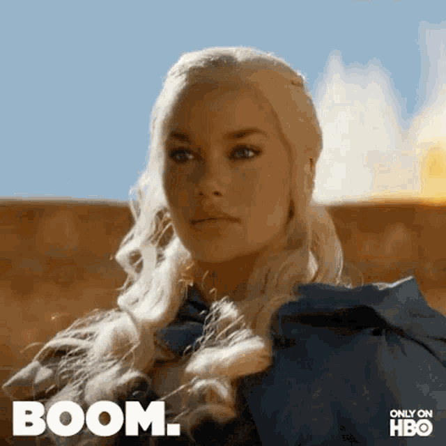 a woman with blonde hair is standing in front of a fire and the word boom is on the bottom of the image