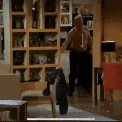 a shirtless man is walking through a living room .