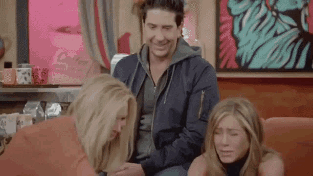 a man and two women are sitting on a couch and laughing .