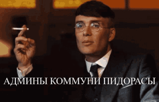 a man in a suit and tie smoking a cigarette with the words admini kommyni pidopacy written below him