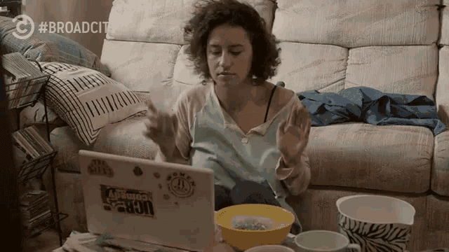 a woman sitting on a couch using a laptop with a sticker on it that says ' comedy central '