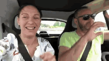 a man and a woman are sitting in a car . the man is wearing sunglasses and the woman is smiling .