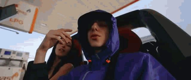 a man in a purple jacket is sitting in a car with a woman