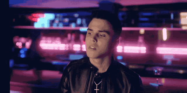 a man wearing a black leather jacket with a cross necklace