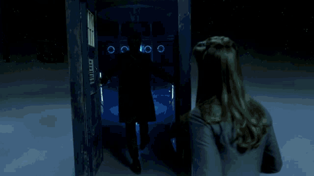 a man in a black coat stands in front of a glowing green object