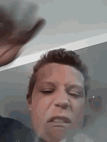 a close up of a person 's face with a reflection of their hand