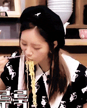 a woman wearing a black hat is eating ramen with chopsticks