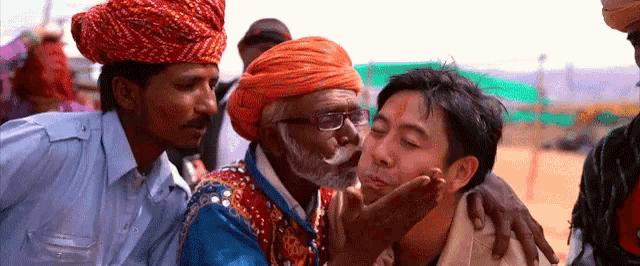 a man kisses another man on the cheek in a crowd of people