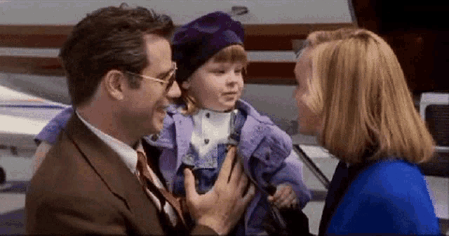 a man in a suit and tie holds a little girl in his arms
