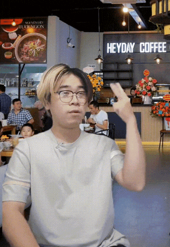 a man giving the middle finger in front of a sign for heyday coffee