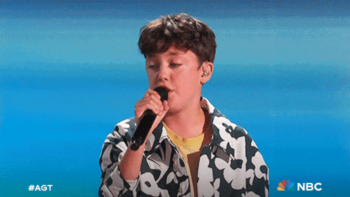 a young boy singing into a microphone with the nbc logo in the corner