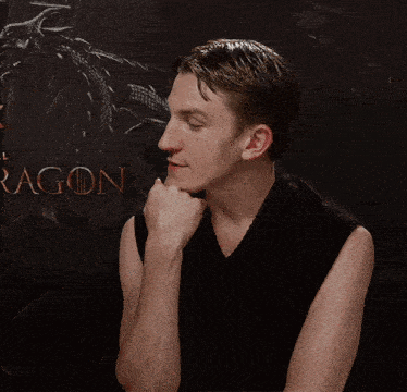 a man in a black tank top is talking in front of a dragon poster