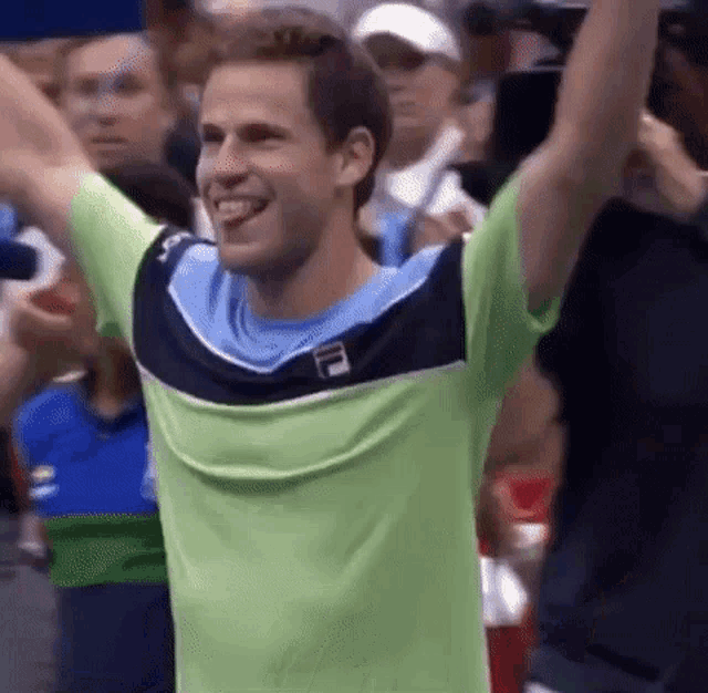 a man in a fila shirt is raising his arms in the air